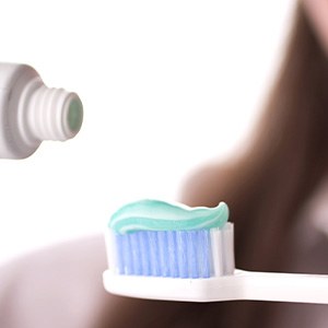 Lady applies toothpaste to brush