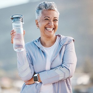 Woman smiling with water bottle on hike outside