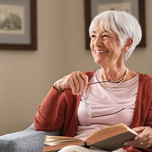 Woman smiling while reading book on couch at home