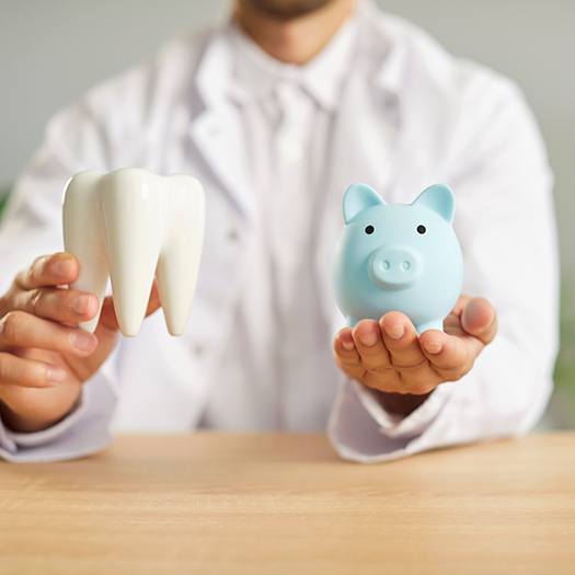 a dentist holding a model tooth and a piggy bank
