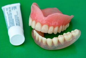 Tube of denture adhesive next to dentures.